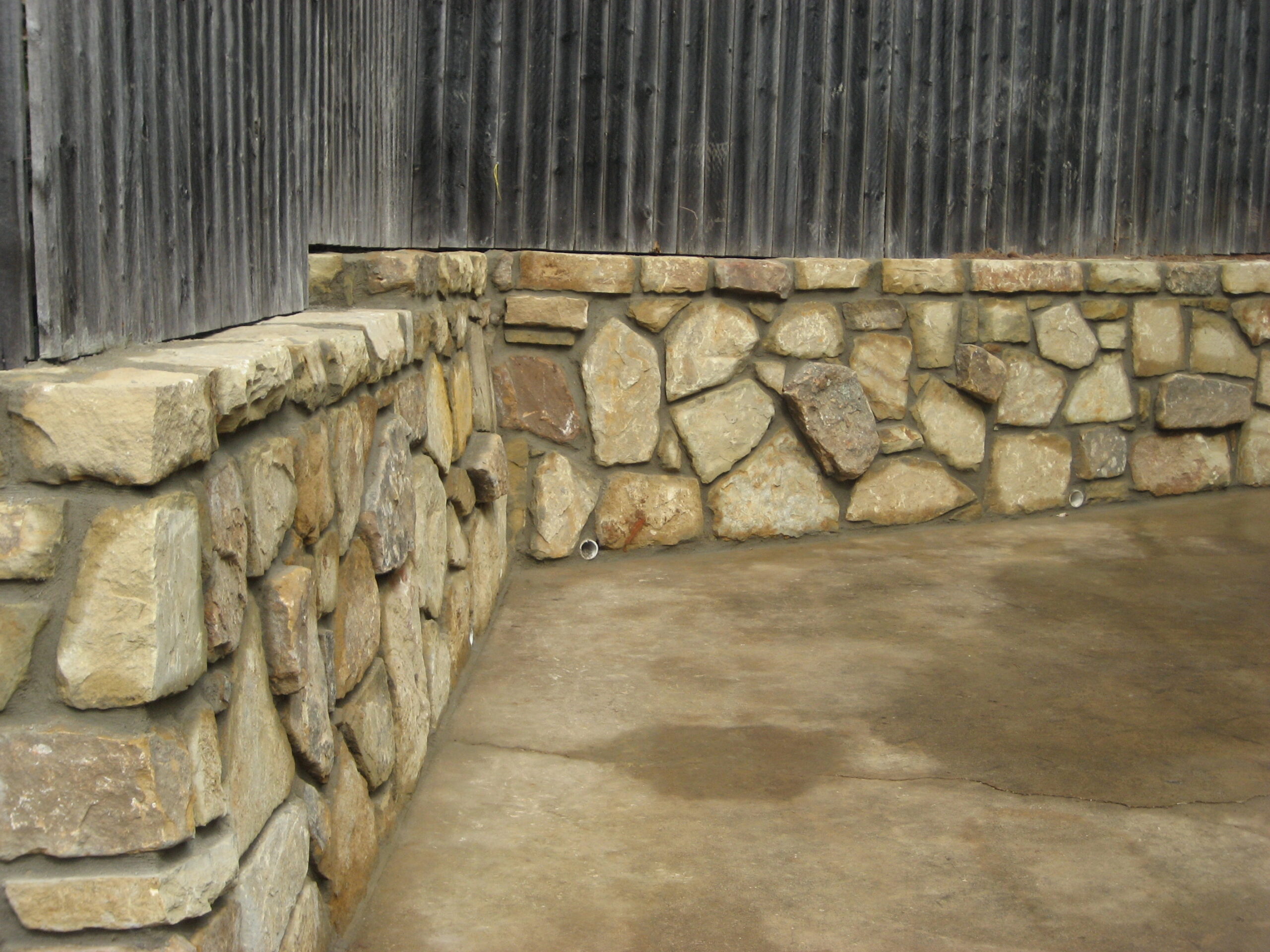 Rock retaining wall with wood privacy fence in this Dallas home.