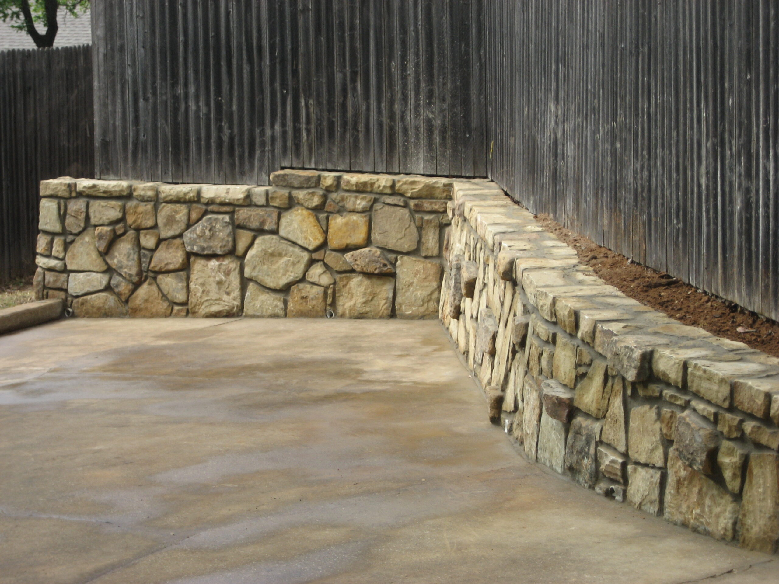 Rock retaining wall with privacy fence in Dallas, Texas home.