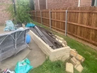 Cinder Block Retaining Wall Installation – Colleyville TX Cinder block retaining wall under construction along backyard fence line in DFW, with old railroad-tie materials removed and new block courses set