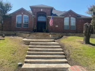Staircase & Retaining Wall Replacement | Carrollton TX New stone stair steps leading to brick home entrance after retaining wall and staircase replacement in Carrollton, TX