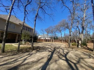 Cleared residential backyard in Keller TX after complete pool and pool deck removal, leaving a level graded open yard with mature oak trees