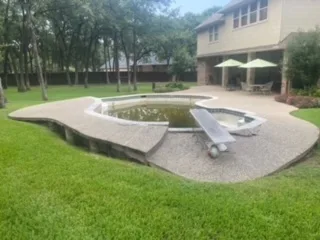 Concrete in-ground pool with curved deck and slide in a Keller TX backyard, scheduled for complete pool removal by JCL Landscape Services