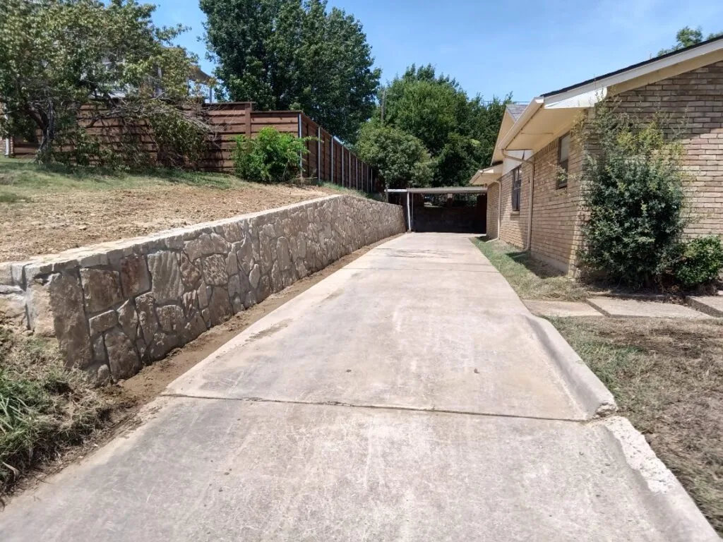 Milsap Stone Retaining Wall Replacement | Irving TX Newly built Milsap stone retaining wall along concrete driveway replacing old concrete wall at Irving TX home