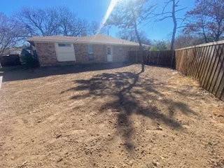 Completed pool removal in Coppell TX — bare dirt backfill and finish grading where an inground pool once stood beside a brick ranch home