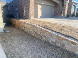 Milsap stone retaining wall extension along residential driveway in Colleyville TX, adding 2 feet of new stone to existing wall