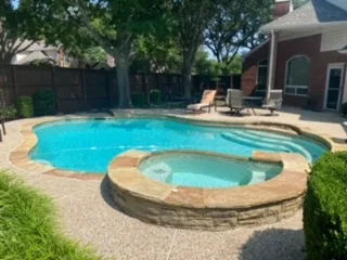 Freeform backyard pool with attached spa and tan stone coping at a Plano, TX home scheduled for professional pool removal