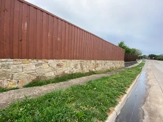 Milsap Stone Retaining Wall with Wood Fence | Carrollton TX Milsap stone retaining wall base supporting a wood privacy fence along a residential street in Carrollton, TX
