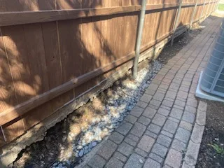 Failing Railroad Tie Wall Before Replacement – Allen TX Failing railroad tie retaining wall crumbling along a brick paver path beside a wood fence in Allen, TX — before replacement