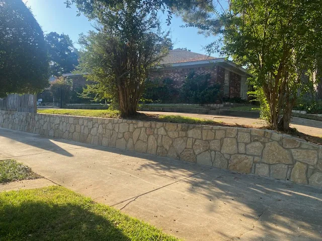 Completed Milsap stone retaining wall along a residential driveway in Arlington TX, replacing an old concrete wall