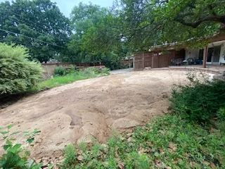 Backfilled and finish-graded yard after partial pool removal in Dallas TX, showing smooth sandy soil ready for landscaping near a brick home