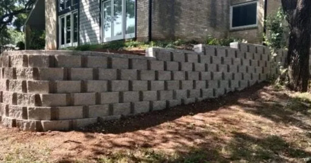 Large concrete block retaining wall along residential home foundation in Highland Village TX, engineered for DFW clay soil erosion control