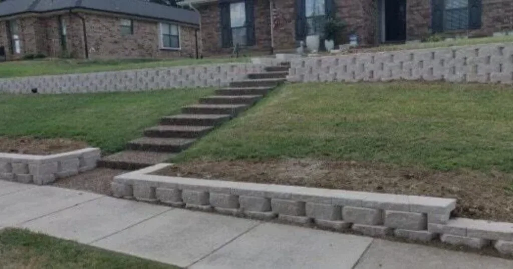 Tiered concrete block retaining walls with integrated staircase replacing old crosstie wall at a brick home front yard in Carrollton, TX