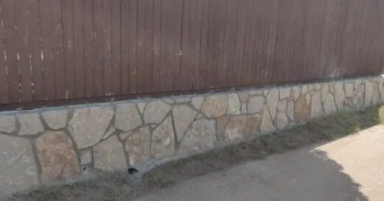 Low natural stone retaining wall with irregular flagstone pattern supporting a wood fence along a residential property in Carrollton, TX