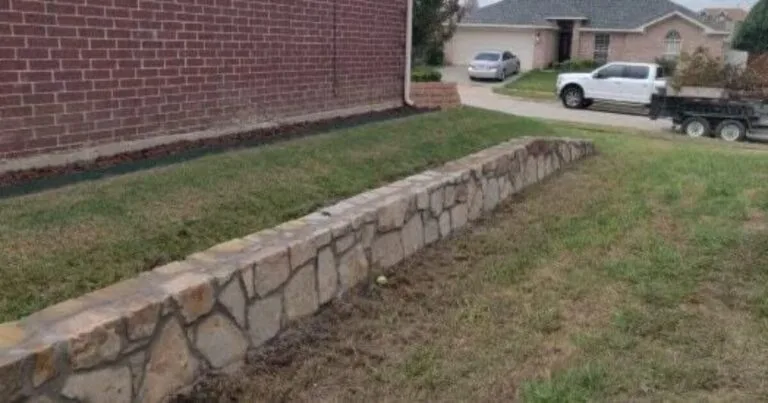 Newly built natural stone retaining wall along a brick home's front yard in Arlington TX, replacing an old crosstie wall