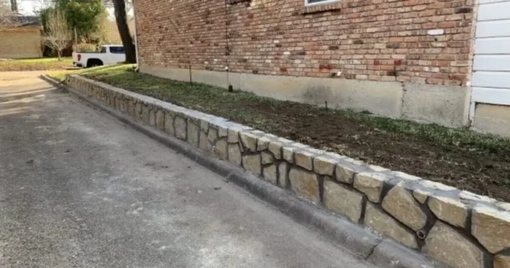 New Granbury stone retaining wall along brick home driveway, replacing a deteriorated wood wall in Dallas, TX