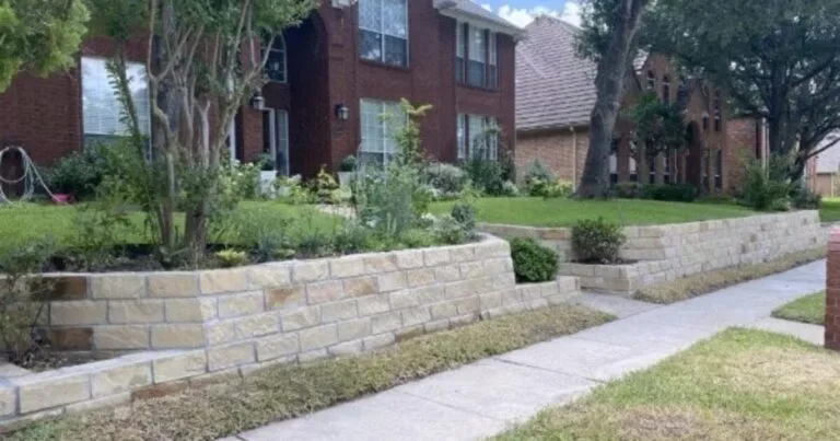 New Granbury stone retaining wall replacing old crosstie wall along front yard of brick home in Plano, TX, with lush planted beds above.
