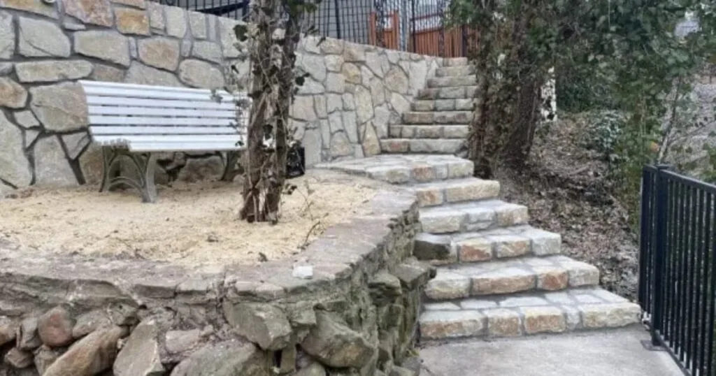 Old crumbling stone retaining wall beside new Milsap stone retaining wall with matching stone steps and white bench in Richardson, TX