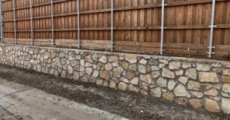Milsap stone retaining wall replacing old cross ties along a cedar wood fence in Carrollton, TX residential backyard