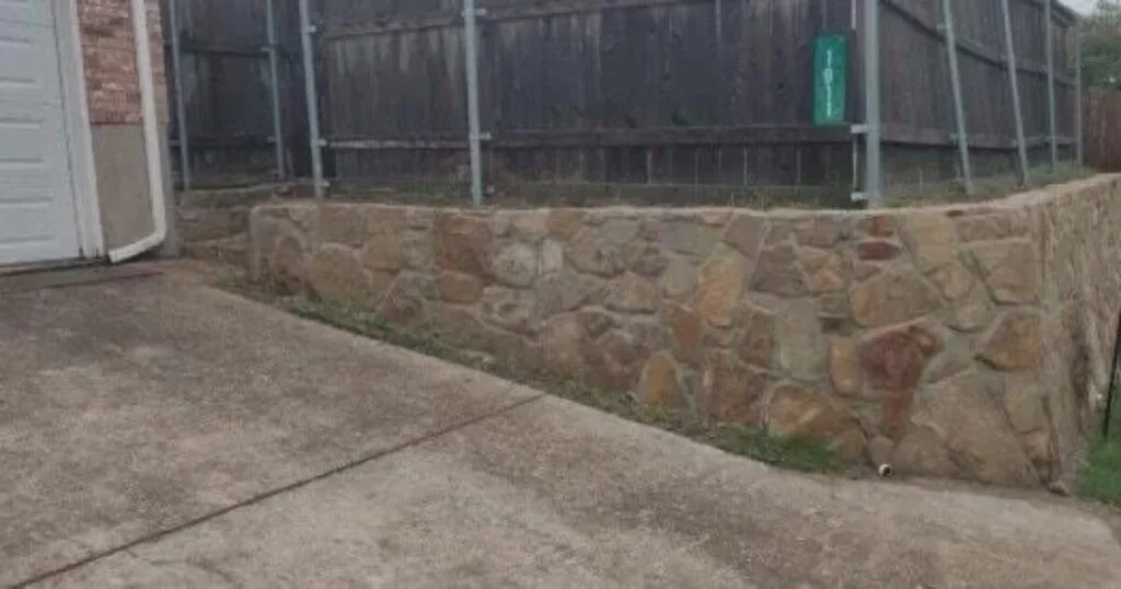 Milsap stone retaining wall along residential driveway in Carrollton TX, replacing an old crosstie wall beside a garage and wood fence
