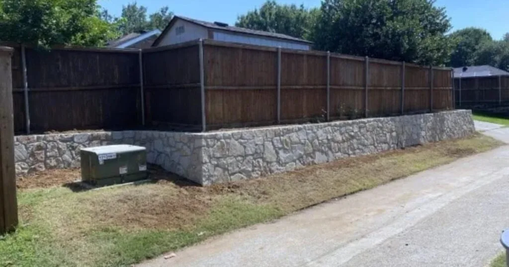New Milsap stone retaining wall supporting a wood privacy fence along a residential property edge in Coppell, TX