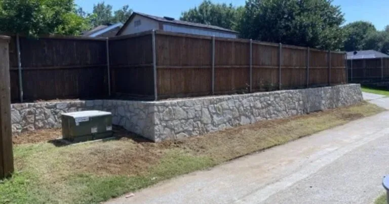 New Milsap stone retaining wall supporting a wood privacy fence along a residential property edge in Coppell, TX