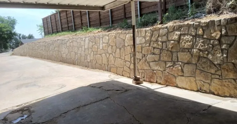 Milsap stone retaining wall along a residential driveway in Irving, TX, replacing an old concrete wall on a sloped hillside