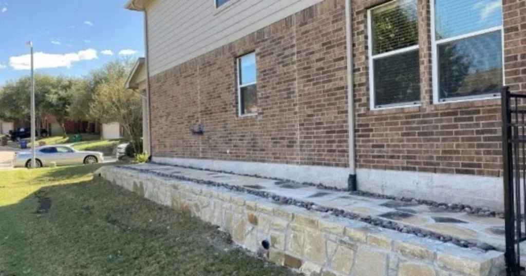 Milsap stone retaining wall with Oklahoma flagstone walkway and river rock border along brick home's foundation in DFW
