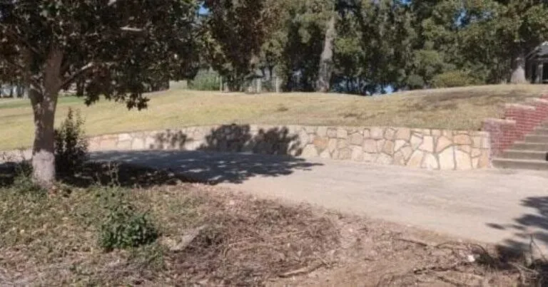 Curved Milsap stone retaining wall replacing old brick wall on sloped residential yard in Flower Mound, TX