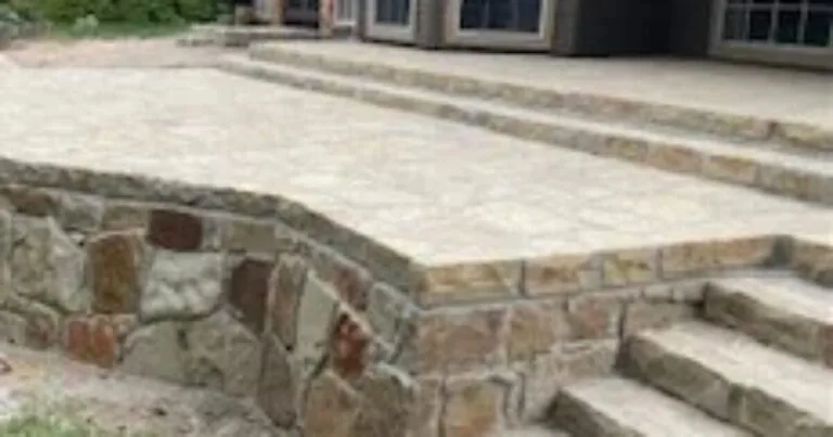 Tiered Milsap stone retaining wall with integrated steps and stamped concrete patio replacing a failing cross-tie wall at a DFW home