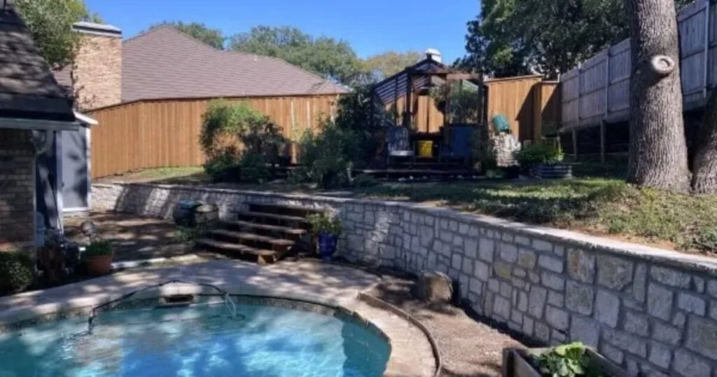 Stone retaining wall with stair steps separating pool patio from upper yard in Arlington TX DFW home