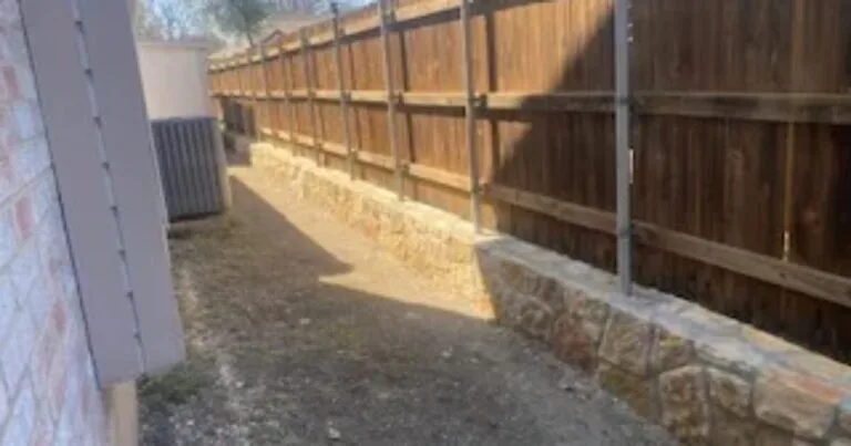 Completed Milsap stone retaining wall along residential wood fence line, replacing old railroad ties in Allen, TX