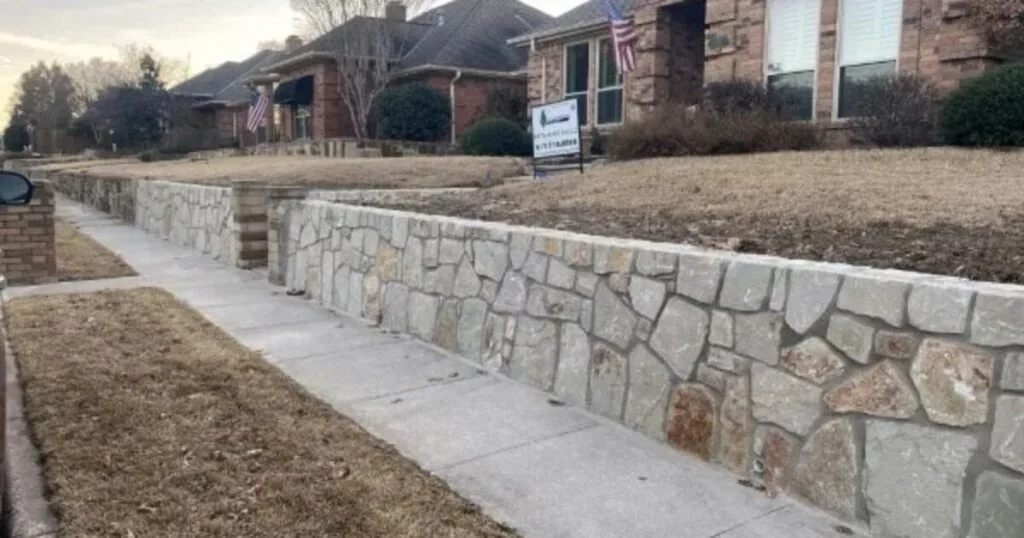 Newly built Milsap stone retaining wall along a residential sidewalk in Bedford, TX, replacing an old brick wall