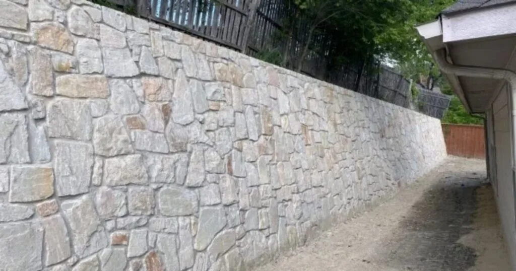 New Milsap stone retaining wall running along residential property in Dallas, TX, replacing a failed crosstie wall