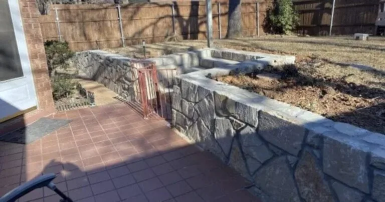 New Milsap stone retaining wall replacing a failed wood crosstie wall along a backyard patio in Highland Village, TX