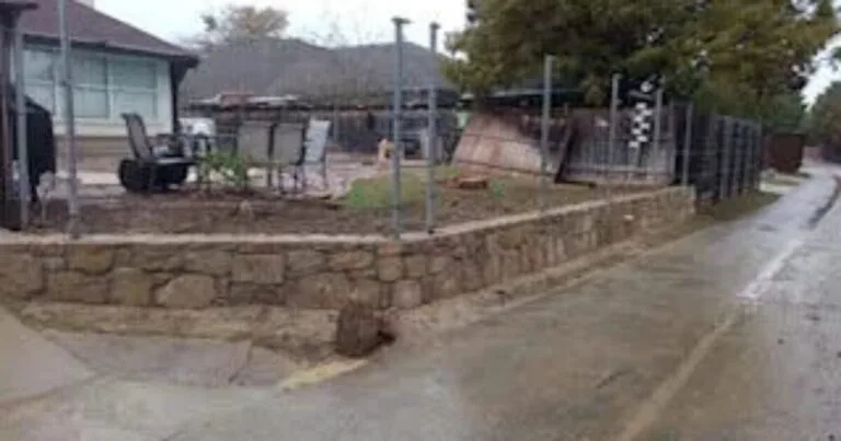 Curved Milsap stone retaining wall replacing a failed wood wall along a residential street in Lewisville, TX