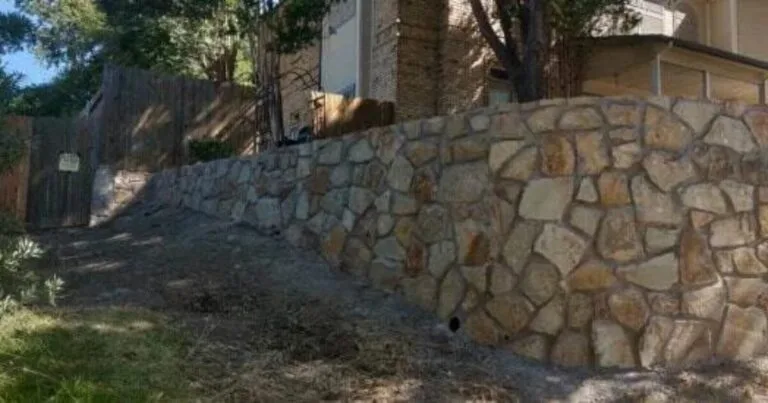 Engineered Milsap stone retaining wall along a sloped residential yard in Lewisville TX, holding back DFW clay soil near a brick home