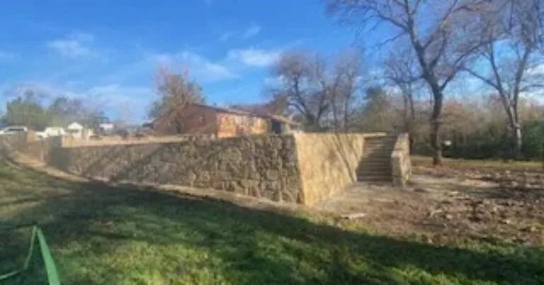 Newly constructed Milsap stone retaining wall with built-in steps holding back a raised yard beside a residential home in DFW