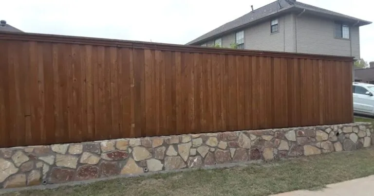 Milsap stone retaining wall base supporting a stained wood privacy fence along a residential property line in DFW
