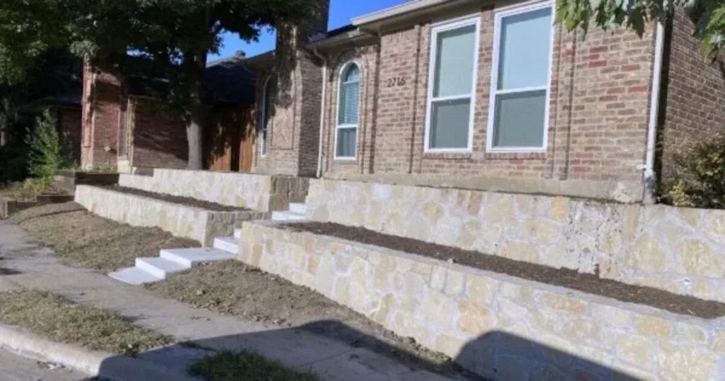 Tiered Milsap stone retaining walls with concrete steps at a brick home in Dallas, TX, rebuilt by JCL Landscape Services