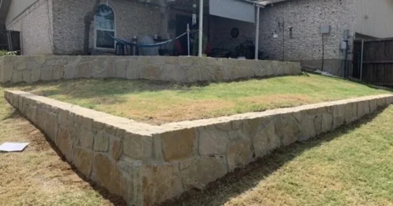 Two-tier Milsap stone retaining wall forming a raised backyard terrace behind a brick home, replacing old cross-tie walls in DFW