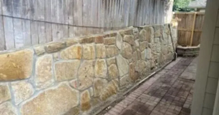 Newly built Milsap stone retaining wall along a brick paver pathway beside a wood fence, replacing a railroad tie wall in Dallas, TX