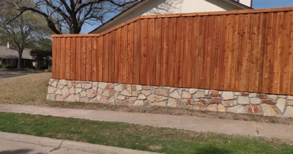 Stone retaining wall base topped with cedar wood privacy fence along a residential street in Plano, TX