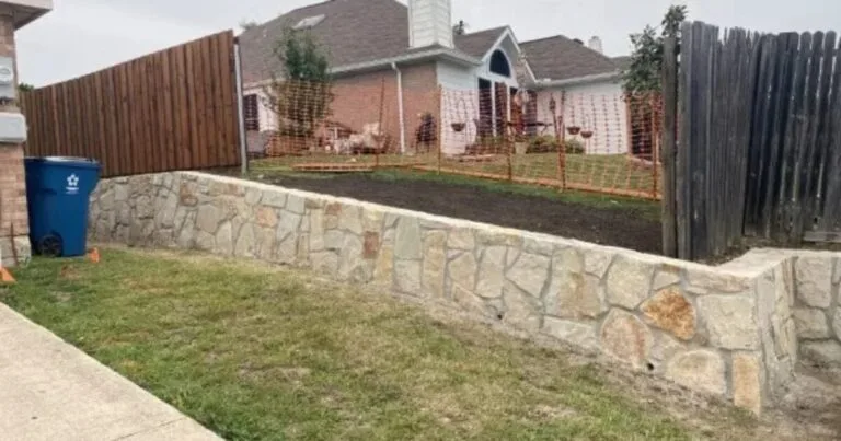 Newly built natural stone retaining wall replacing old crossties along a residential backyard in Lewisville, TX