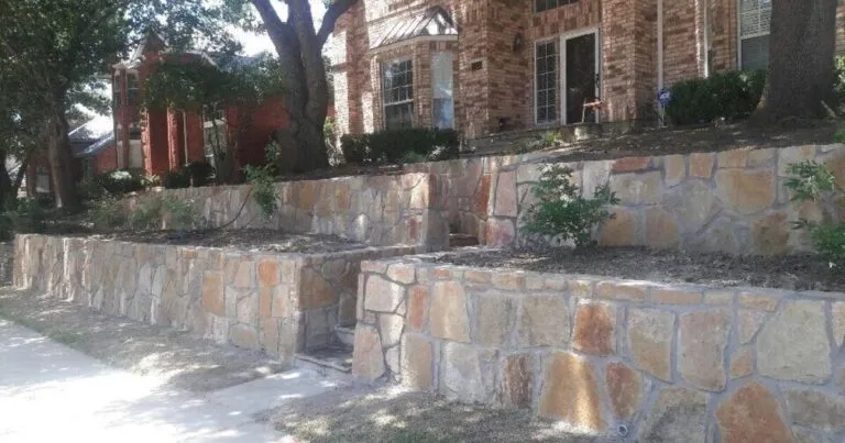 Two-tier Granbury stone retaining wall terracing a sloped front yard at a brick home in Dallas, TX
