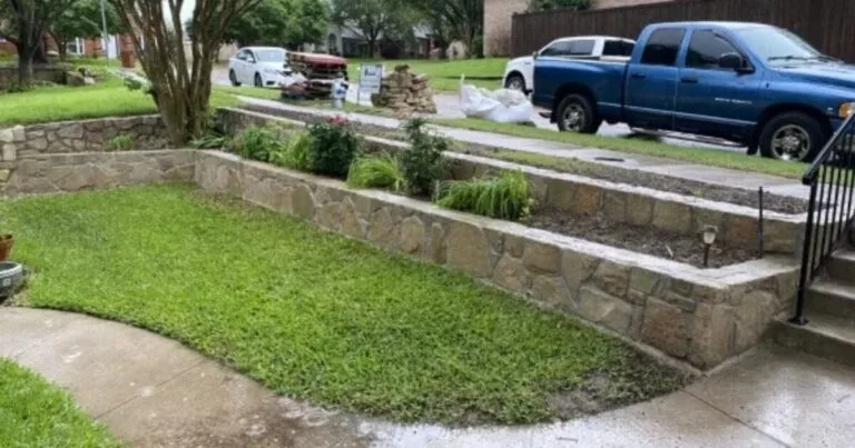 Tiered natural stone retaining wall with planting beds along a residential front yard in McKinney, TX, during active replacement project