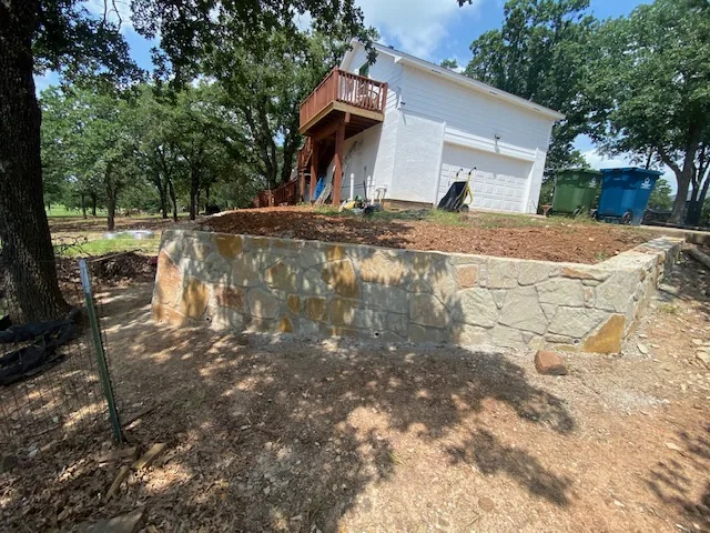 Finished tiered natural stone retaining wall and regraded slope in Argyle Texas