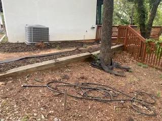 Failing timber retaining wall and eroded bank beside a house in Argyle Texas