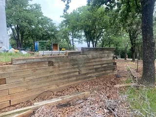 Rotted tiered timber retaining wall losing its line on an Argyle slope