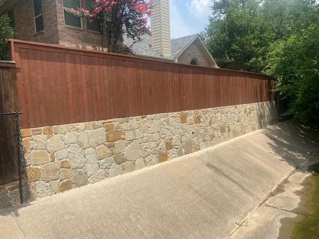 New Milsap stone retaining wall — Colleyville TX New Milsap stone retaining wall and cedar fence along a Colleyville driveway