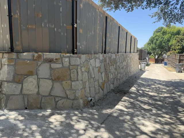 New natural stone retaining wall built along a Dallas driveway replacing a railroad tie wall